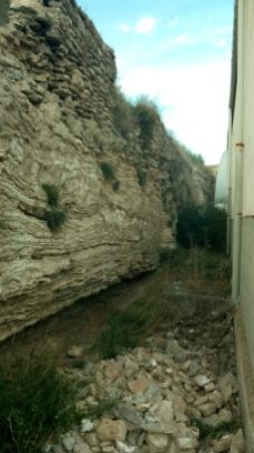 Muralla excavada en la roca con parapeto arriba de un metro, se puede ver como poco a poco se van derruyendo